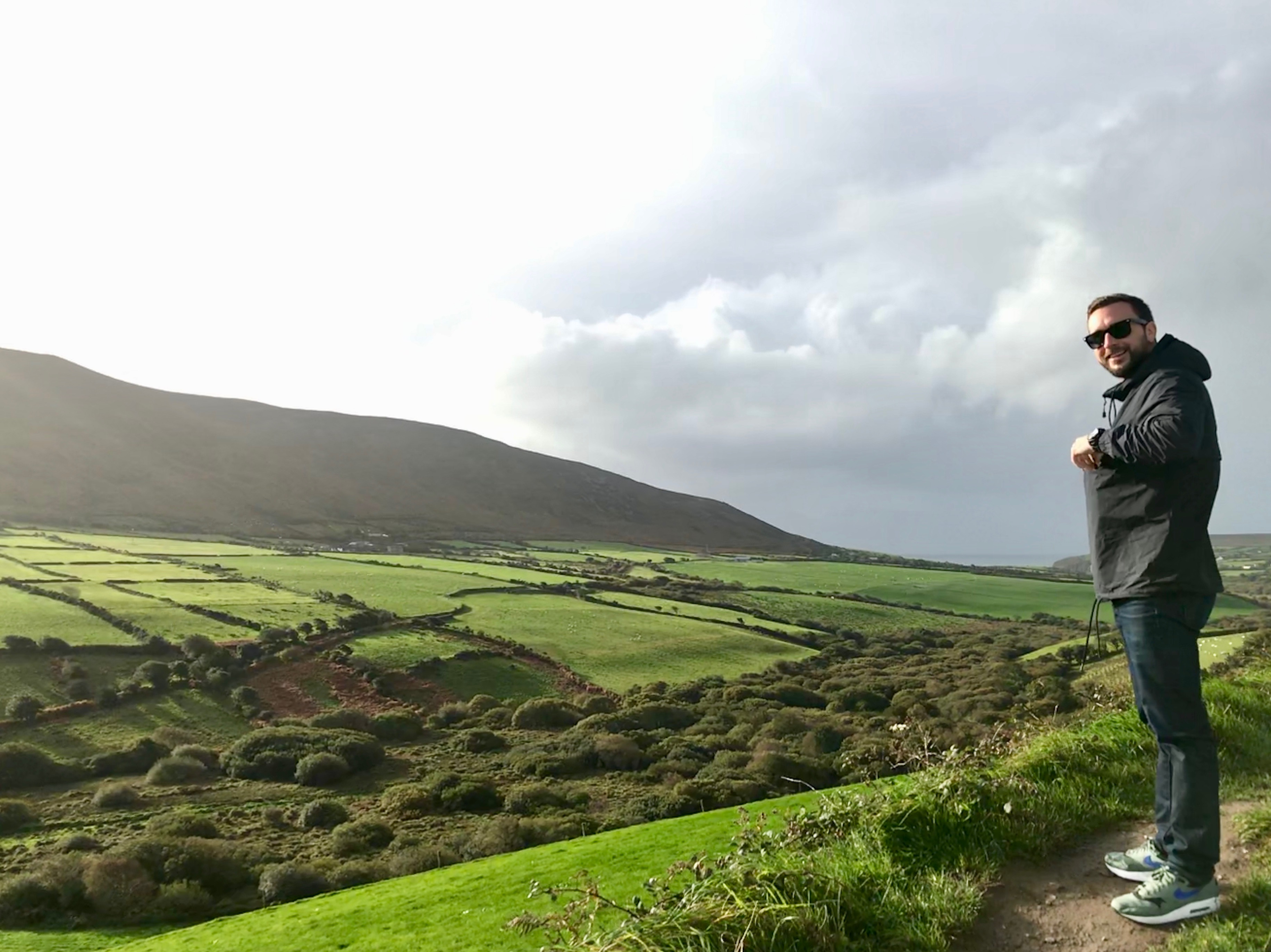 Chris standing over green fields in Ireland